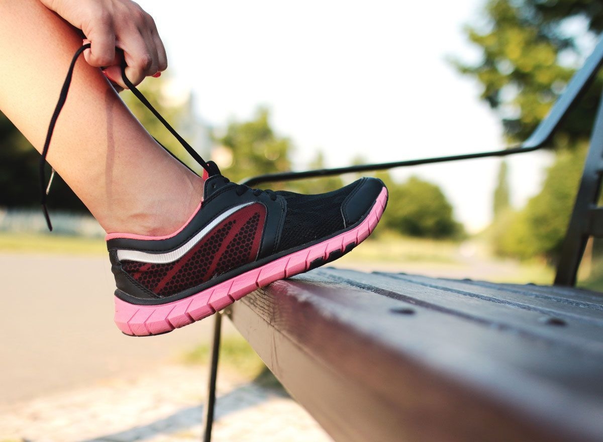 Person tying their running shoe on a bench