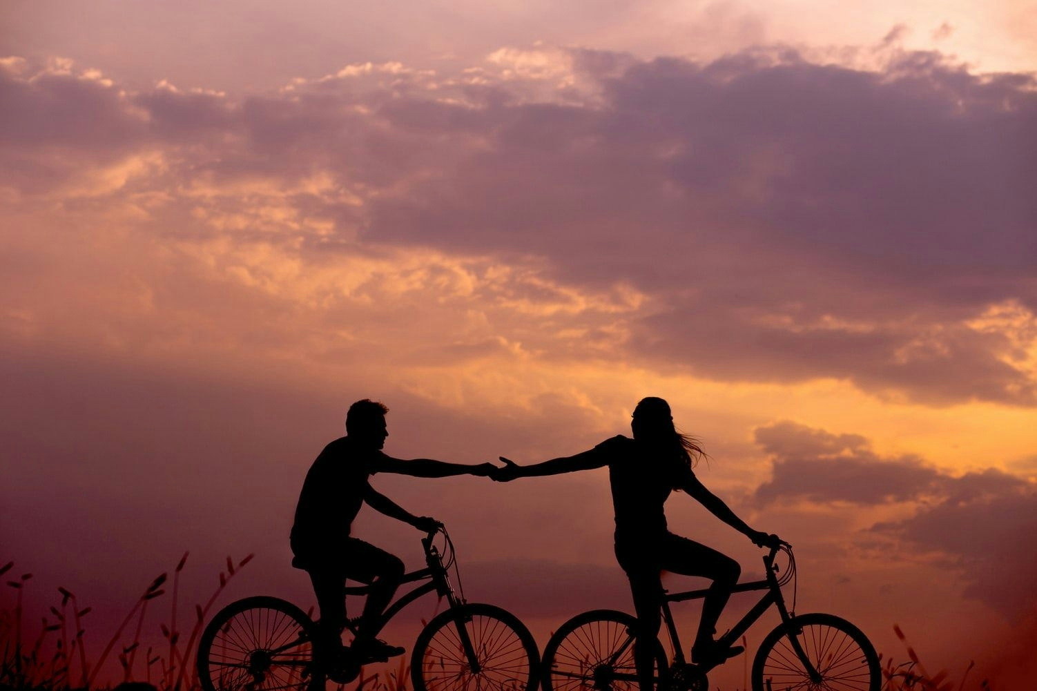 2 people touching hands while bike riding